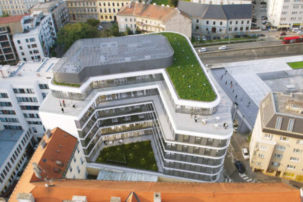 Na fotografii dobre vidieť tvar budovy a zelenú strechu.
