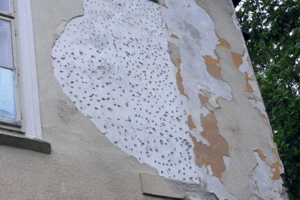 Samovoľné odpadnutá vrchná vrstva fasádovej omietky ktorá odhalila existenciu staršej omietkovej úpravy na povrchu pamiatkovej budovy.