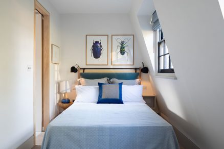 Umelecké plagáty a textílie na posteli dopĺňajú svetlú paletu farieb v spálni