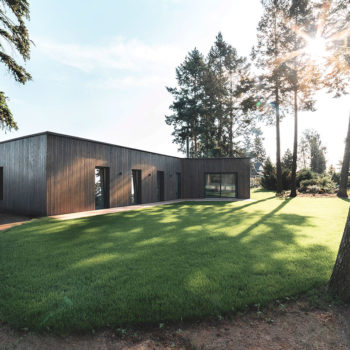 Projekt bungalova pôsobí v prírodnom prostredí nenápadne s okolím splýva i vďaka tmavej drevenej fasády.