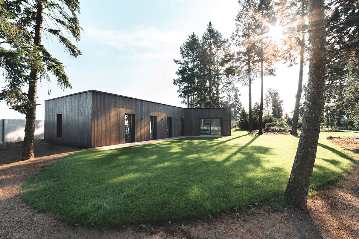 Projekt bungalova pôsobí v prírodnom prostredí nenápadne s okolím splýva i vďaka tmavej drevenej fasády.