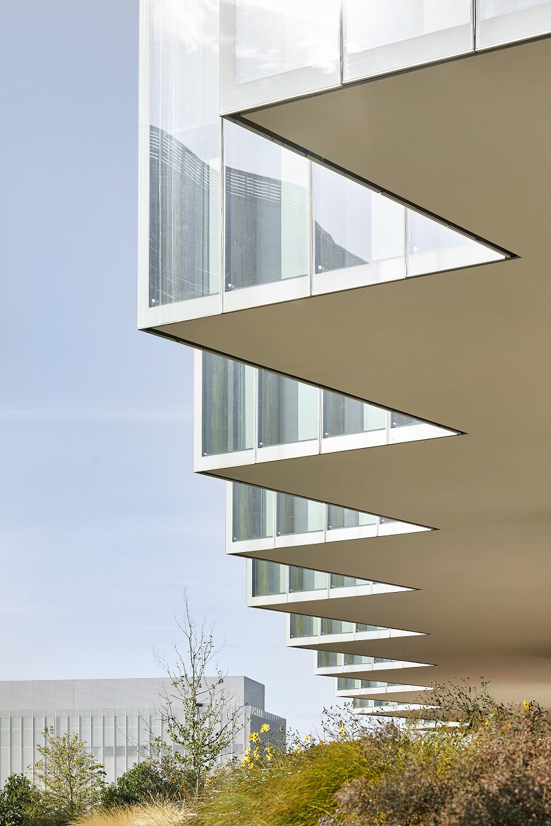 Nová budova má tvar trojuholníkového skleneného kotúča so zaoblenými hranami, ktorý voľne kopíruje tvar lokality.