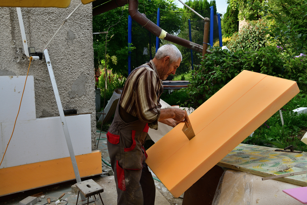 The mason saw by hand polystyrene to insulate the walls of the house