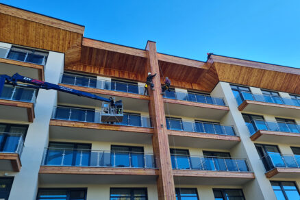 Tím výškových pracovníkov MANKI na modernom apartmánovom dome pri údržbe drevených a sklenených prvkov fasády.