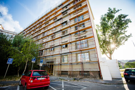 Zatepľovanie bytového domu s použitím EPS, budova so stavebným lešením v procese renovácie