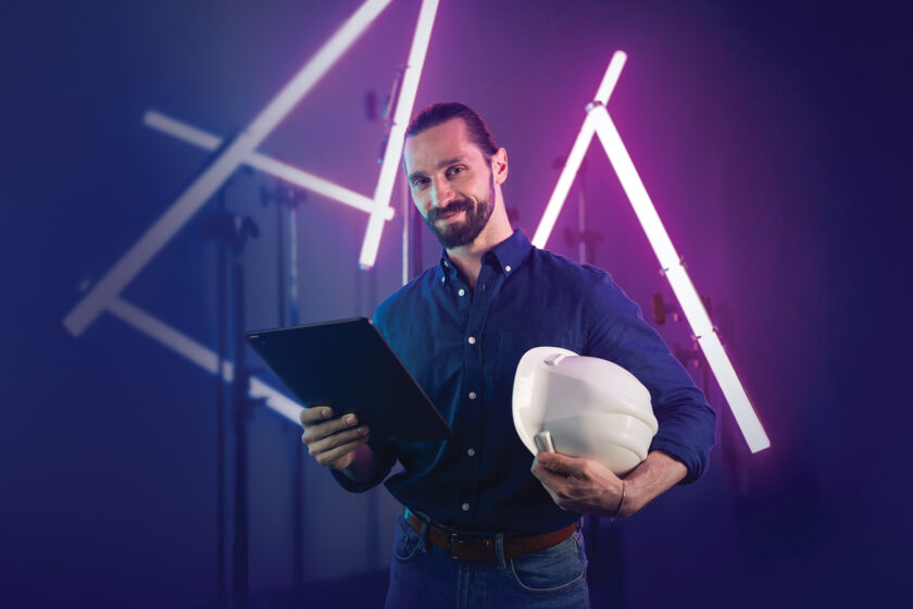Stavbár s tabletom a prilbou v modernom digitálnom prostredí – symbol prepojenia technológií a stavebníctva
