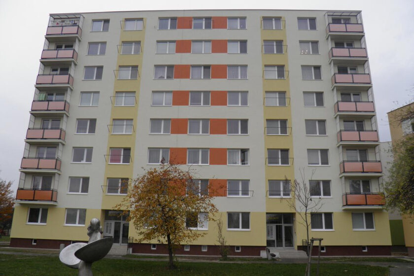 Modernizovaný bytový dom po obnove, zateplená fasáda so satelitmi a novými oknami