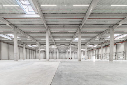Interiér modernej logistickej haly s betónovými stĺpmi a LED osvetlením v Slovinsku