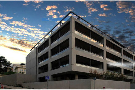 Večerný pohľad na architektonicky výraznú budovu Hausberg s minimalistickým betónovým dizajnom