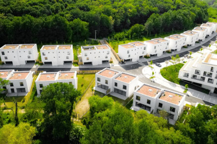 Letecký pohľad na modernú štvrť s radovou zástavbou bielych rodinných domov obklopených zeleňou