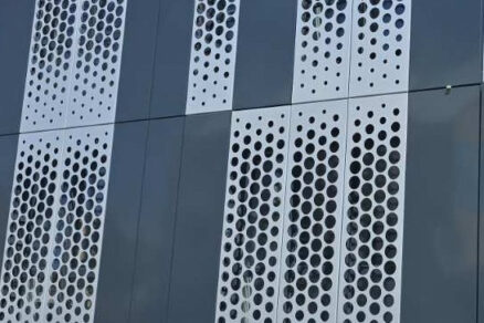 Detail perforovaných plechov na modernej fasáde budovy s vertikálnym usporiadaním otvorov