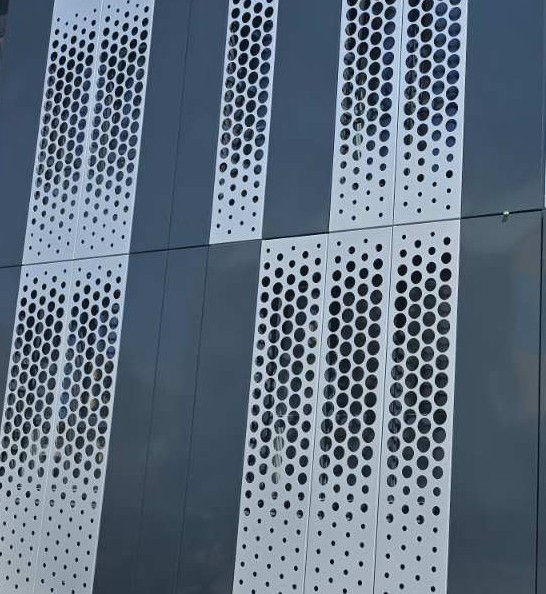 Detail perforovaných plechov na modernej fasáde budovy s vertikálnym usporiadaním otvorov
