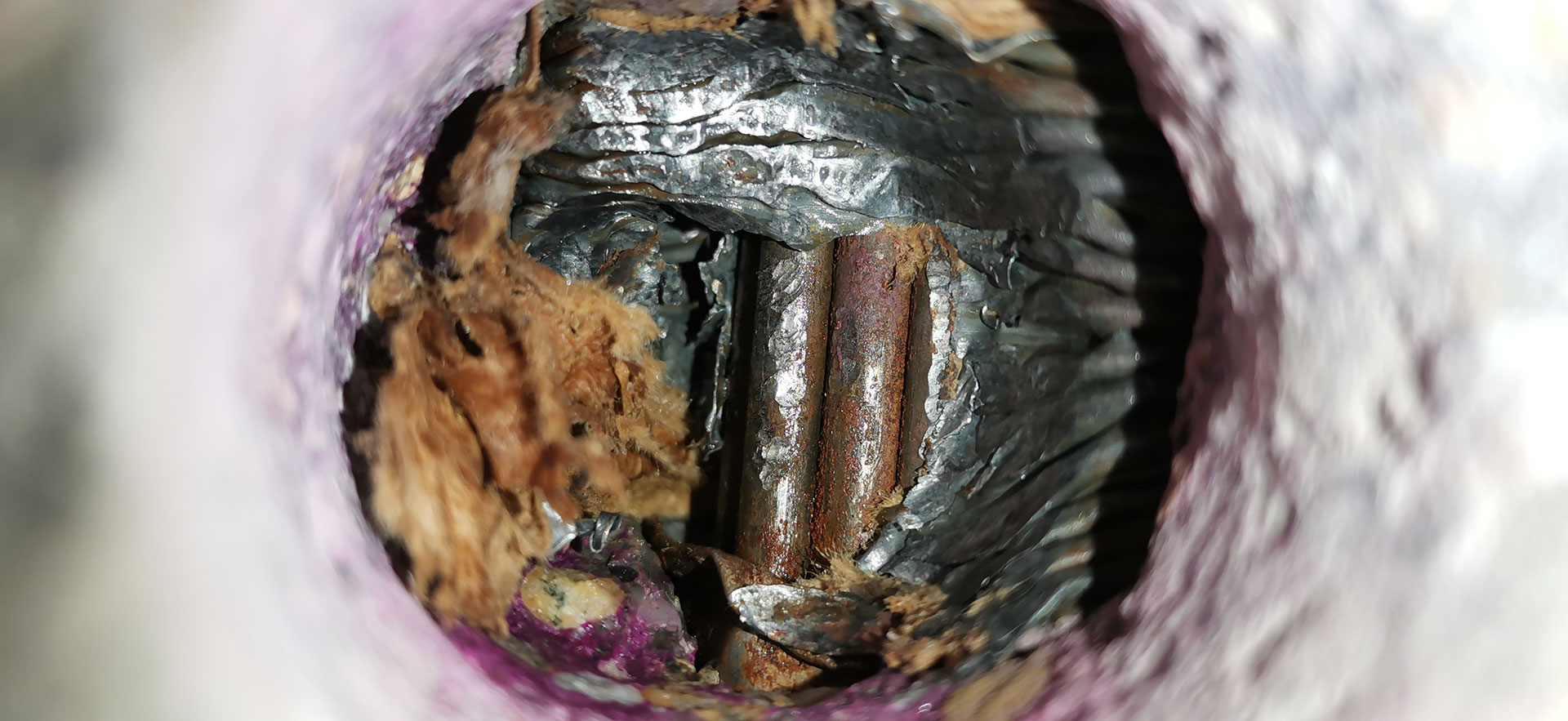 Obr. 3 Pohľad do vŕtanej sondy v mieste škáry medzi segmentmi – na obrázku vidieť kartónové spojky; 
c) možno pozorovať mokrú kartónovú spojku a začínajúcu koróziu nezainjektovaných drôtov
