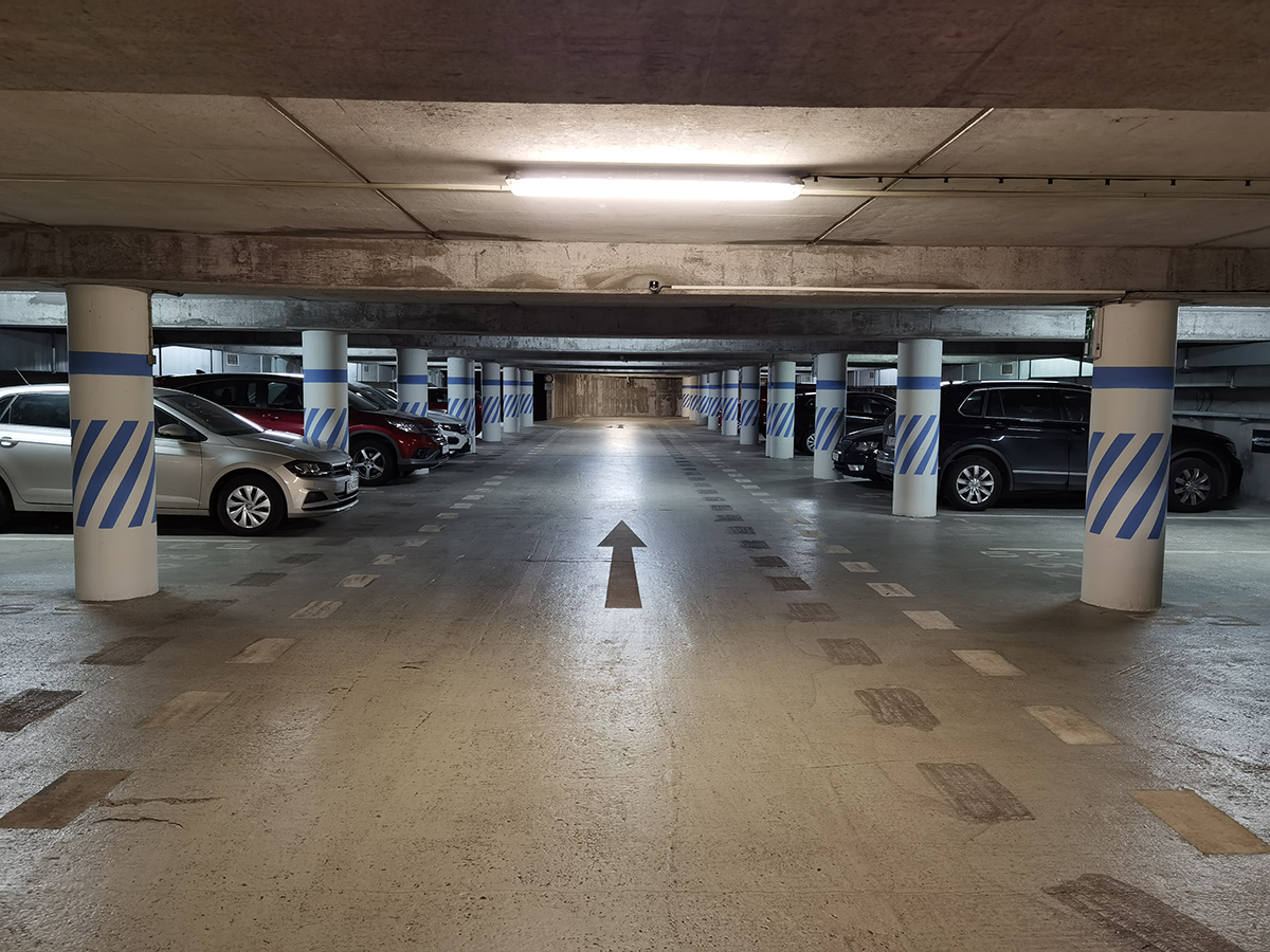 Osvetlená podzemná garáž so značením parkovacích miest a smerovou navigáciou