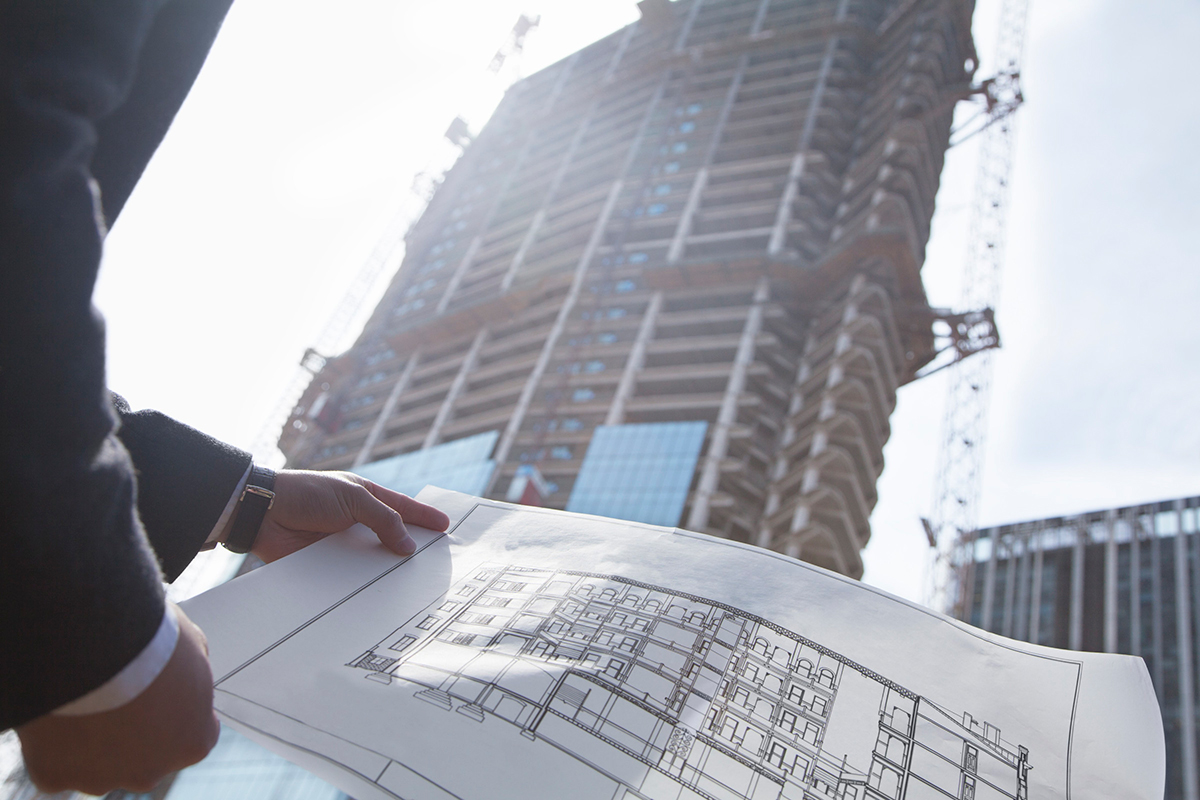 Architekt porovnáva projektovú dokumentáciu s aktuálnou výstavbou administratívnej budovy