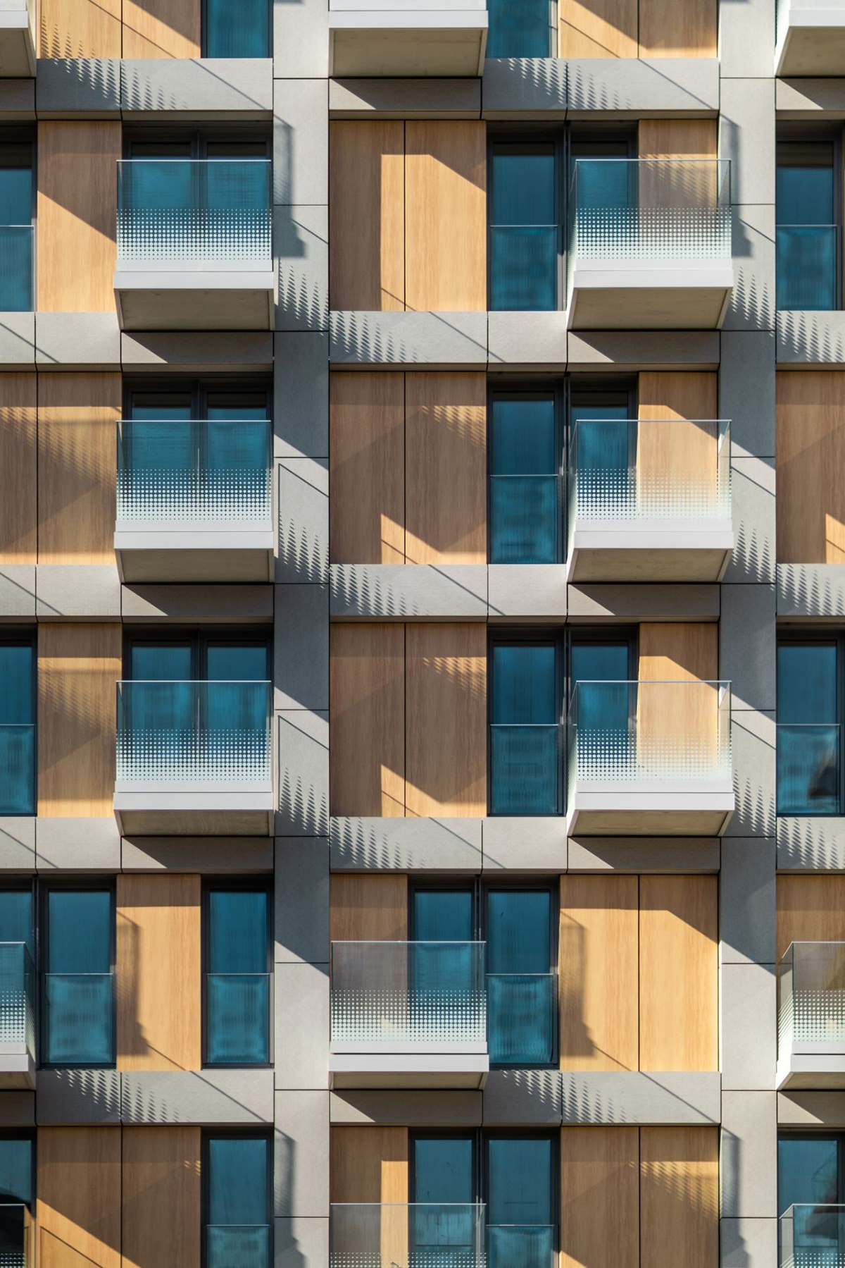 Detail rezidenčnej fasády s dreveným obkladom a modernými balkónmi