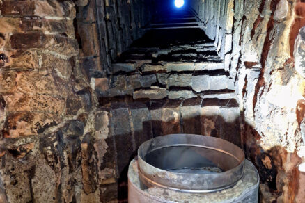 Pohľad zdola na murovaný komín a pôvodný dymovod z nehrdzavejúcej ocele s tepelnou inštaláciou (bol odstránený)