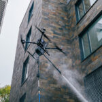 Dron pri čistení fasády administratívnej budovy vysokotlakovým systémom