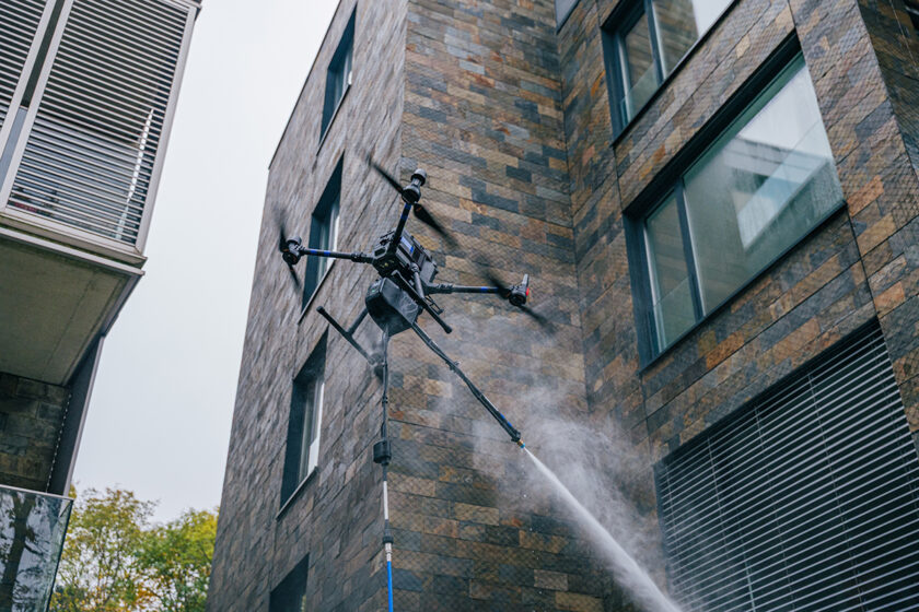 Dron pri čistení fasády administratívnej budovy vysokotlakovým systémom