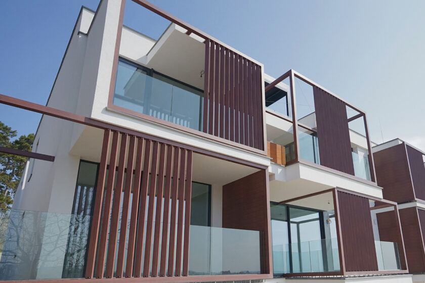 Sklenené zábradlia na modernom rezidenčnom objekte s drevenými lamelami na fasáde