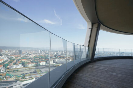 Oblúkové sklenené zábradlie na terase výškovej budovy s panoramatickým výhľadom