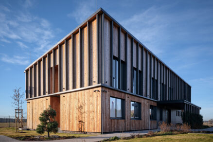 Moderná administratívna budova s vertikálnym dreveným a vláknocementovým obkladom fasády