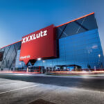 Sklenená fasáda nového obchodného domu s logom XXXLutz v Nitre počas večera