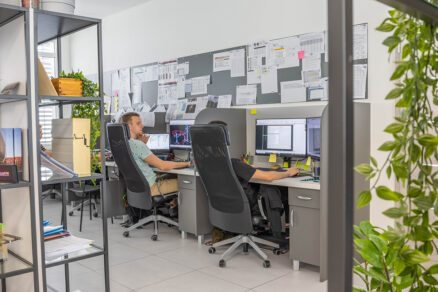 Projektanti a konštruktéri pri práci v moderne vybavenej kancelárii s technickými výkresmi a CAD softvérom.