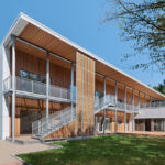 Drevená montovaná budova so svetlými vláknocementovými panelmi a vonkajším schodiskom