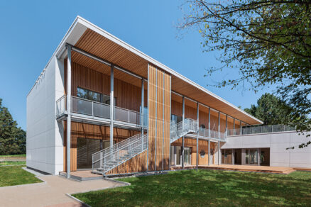 Drevená montovaná budova so svetlými vláknocementovými panelmi a vonkajším schodiskom