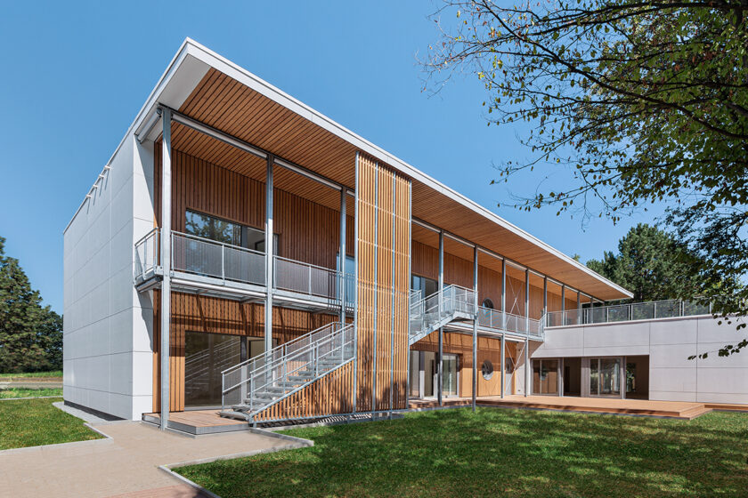 Drevená montovaná budova so svetlými vláknocementovými panelmi a vonkajším schodiskom