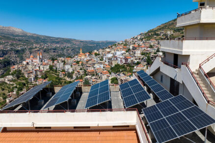 Strešná inštalácia fotovoltických panelov na budove s výhľadom na mesto