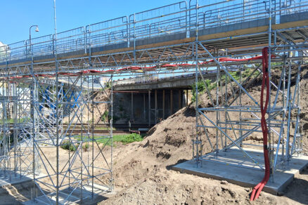 Systémové lešenie Ringlock je nasadené ako dočasný most ponad železnicu, vzadu vidieť starý most v havarijnom stave pred jeho demoláciou.