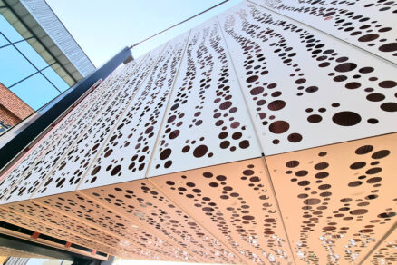 Moderná kovová fasáda s nepravidelným perforovaným vzorom na administratívnej budove
