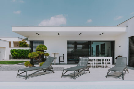 Moderný bungalov so žalúziami na všetkých oknách a terasou pri bazéne