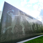 Dizajnová perforovaná fasáda s grafickým motívom športovcov na budove telocvične