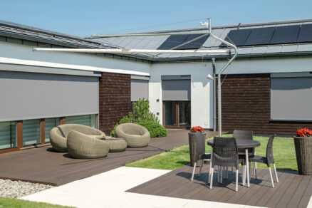 Exteriérové rolety na terase domu s dreveným a bielym obkladom