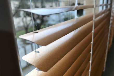 Detail lamiel interiérovej žalúzie pri pohľade zblízka cez okno