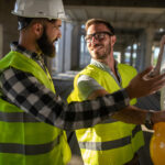 Dvaja stavební inžinieri na stavbe konzultujú výkresy počas technického dozoru