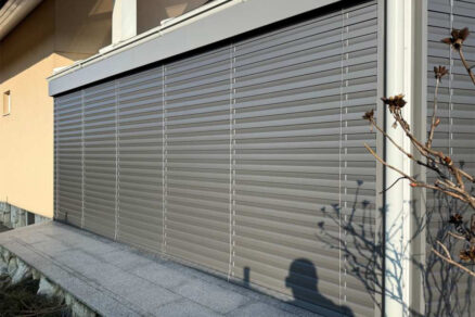Zatienená presklená fasáda s úplne zatvorenými žalúziami v exteriéri