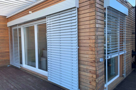 Exteriérové hliníkové žalúzie na drevenej fasáde moderného domu