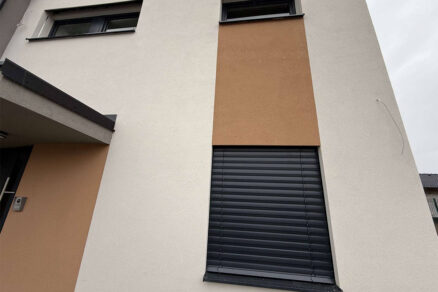 Zatvorené exteriérové žalúzie na okne rodinného domu s farebným kontrastom fasády