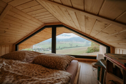 Podkrovná spálňa s atypickým trojuholníkovým oknom a výhľadom do krajiny