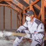 Pracovník aplikuje fúkanú minerálnu izoláciu do väzníkovej strechy
