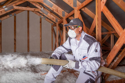 Pracovník aplikuje fúkanú minerálnu izoláciu do väzníkovej strechy