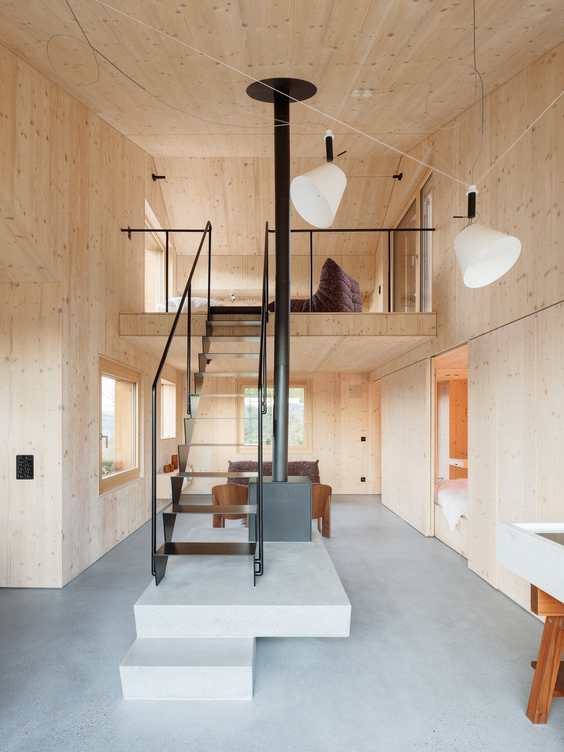 Dominantou vstupnej haly je vyvýšený betónový kubus nesúci krb, z ktorého vyrastá subtílne oceľové schodisko.