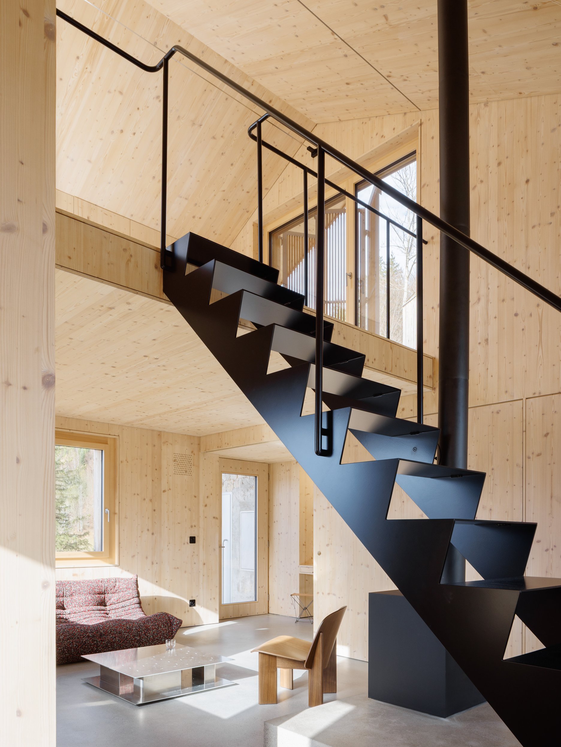 Dominantou vstupnej haly je vyvýšený betónový kubus nesúci krb, z ktorého vyrastá subtílne oceľové schodisko.