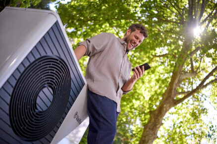 muž ovláda tepelné čerpadlo cez smartfón pri vonkajšej jednotke
