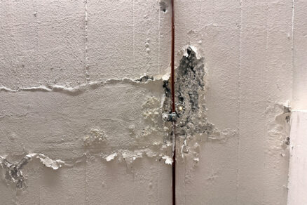 Poškodená stena garáže s odlupujúcou sa omietkou vplyvom vlhkosti a priesaku vody