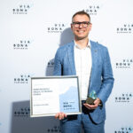 Muž s ocenením za zodpovedné podnikanie stojí pred stenou s logom Via Bona Slovakia